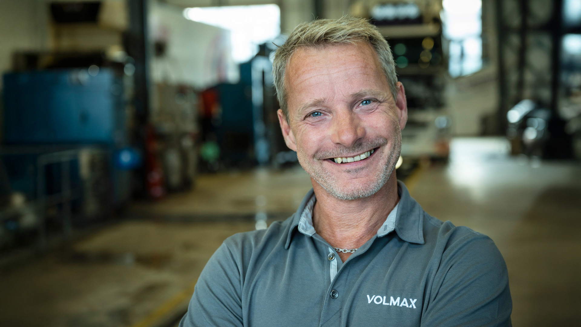 Rådgiver Terje Høitomt i Volmax står i lastebilverkstedet og smiler mot kameraet. Foto